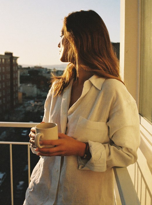 Woman holding a mug on a sunlit balcony